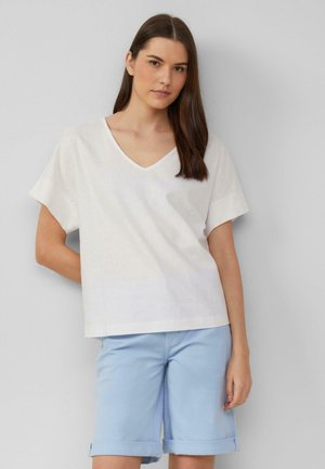 Witte v-halsblouse met korte mouwen, gemaakt van lichtgewicht stof, gecombineerd met lichtblauwe shorts met omslag, gladde textuur, casual ontwerp.