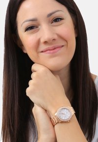 Roségoldene Metalluhr mit rundem Zifferblatt, funkelnden Akzenten und drei Unterdials. Mit einem passenden Armband im Stil einer Bracelet.