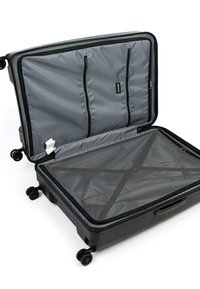 Černý tvrdý kufr s šedým interiérem, který obsahuje síťované zipové kapsy a křížový popruh pro zajištění obsahu. Čtyři kola.