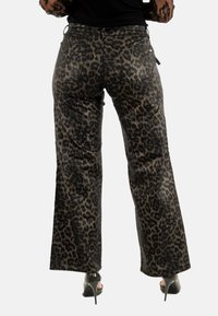 Pantalones de campana con estampado de leopardo y textura brillante, con bolsillos traseros y una cinturilla negra. El patrón consiste en tonos oscuros y claros.