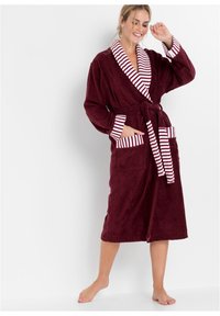 Accappatoio in spugna bordeaux con colletto e polsini a righe. Dotato di vita legata e due tasche frontali. Texture morbida e design fino al ginocchio.