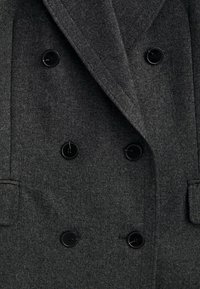 Cappotto doppiopetto in misto lana grigia con bottoni neri, revers e tasche laterali, dal texture morbida.