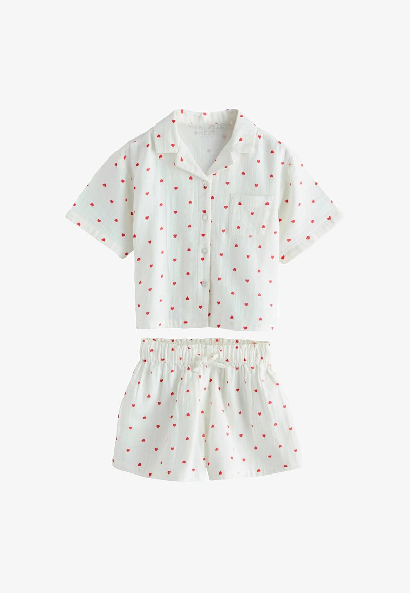 Hvid kortærmet skjorte med knapper og shorts med elastisk talje, begge med lille rødt hjerteprint, designet til afslappet brug.