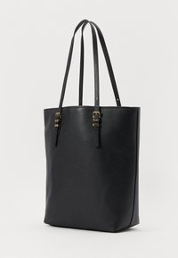 Sac fourre-tout en cuir noir avec deux longues poignées, surface texturée, accents en métal doré et forme cylindrique.