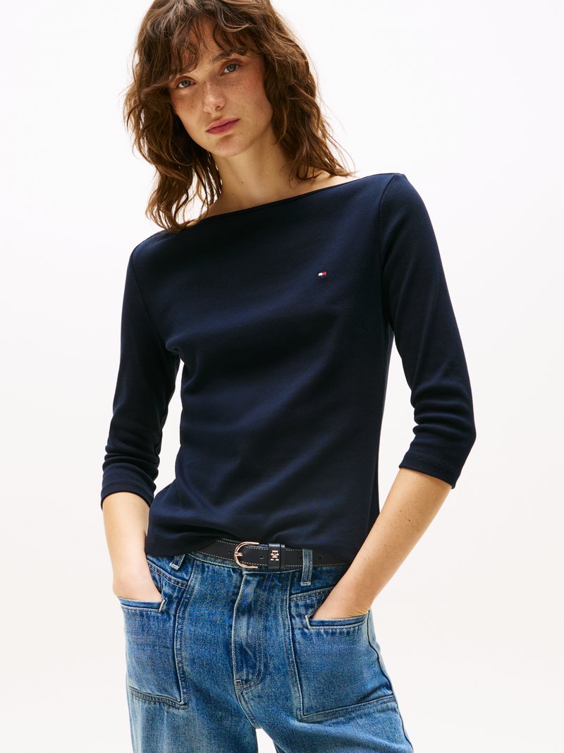 Marineblå langermet topp med båthals, laget av glatte stoffer, kombinert med høyt liv lyse denimjeans med frontlommer.