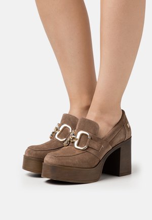 Chaussures compensées en daim marron avec un talon épais, présentant un détail de boucle en or proéminent et une finition lisse et texturée.