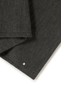 Manta de lana gris oscuro con textura suave, con un borde doblado y una pequeña etiqueta plateada con una letra.