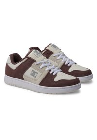 Baskets blanches et brunes avec un mélange de suède et de cuir, présentant un design à lacets, un col rembourré et le logo DC sur le côt�é.