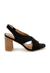 Zwarte suède slingback hak sandaal met een blokhak, open teen, kruislings straps en een geprofileerde houten hak.