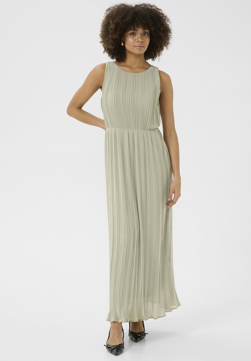 Ljusgrön plisserad maxiklänning med rund halsringning, utan ärmar och en svävande siluett som matchas med svarta skor.