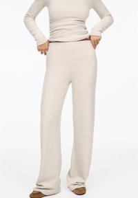 Pantalon de détente en tissu tricoté beige clair avec une coupe décontractée et des jambes droites, doté d'une taille haute et d'une texture douce.