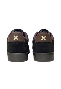 Sneaker in suede nero con accenti marroni, dotate di suola in gomma e un prominente logo "X" dorato sul tallone. Design leggero e a profilo basso.