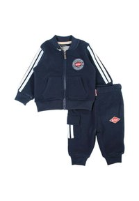 Survêtement de sport bleu marine pour enfants avec une veste à fermeture éclair ornée d'un écusson, un pantalon assorti avec une poche latérale et des bandes blanches sur les manches.