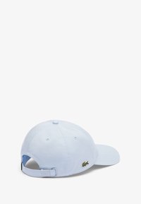 Cappellino da baseball azzurro chiaro in cotone, con un logo di coccodrillo verde ricamato sul lato e una chiusura regolabile sul retro.