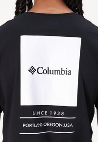 Sort bomulds T-shirt med et hvidt rektangulært grafik, der har "Columbia" logoet og teksten "Siden 1938, Portland, Oregon, USA" centreret nedenunder.