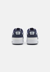 Sneaker blu navy con suole bianche, in materiali scamosciati e tessili, dotate di un logo sul tallone e di un design classico a basse.