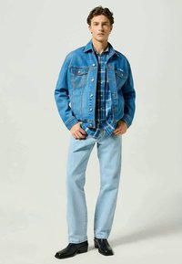 Denim-takki, vaaleansininen ruudullinen paita, vaaleat farkut ja mustat saappaat. Sisältää taskuja, nappeja ja rentoa mitoitusta.