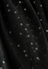 Tissu en maille noire avec des sequins noirs brillants formant un motif tourbillonnant, présentant une finition texturée et des détails de broderie intricats.