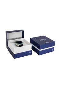 Scatola regalo blu con interno bianco contenente un orologio con quadrante scuro e cinturino nero testurizzato, evidenziato da una lunetta argentata.