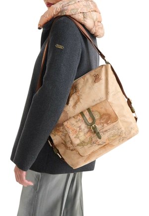 Borsa tote beige con motivo a mappa, dettagli verdi, manici in pelle, tasca frontale e chiusura con zip, indossata sopra un cappotto color carbone.
