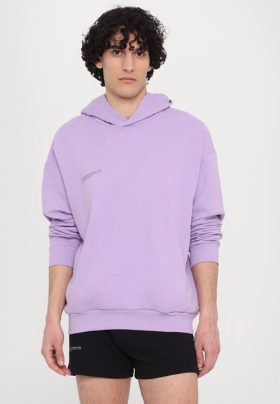 Sweatshirt roxo feito de um tecido macio com capuz ajustável, apresentando um pequeno detalhe de texto impresso no peito e punhos canelados.