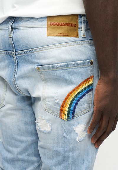 Jean délavé bleu clair avec une broderie arc-en-ciel sur la poche arrière et une étiquette de marque en cuir marron DSQUARED2.