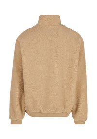 Veste en polaire beige avec un col haut, un ourlet côtelé et des poignets. Matériau doux et texturé avec une coupe décontractée, conçu pour la chaleur et le confort.