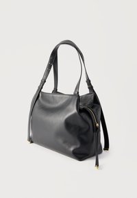 Μαύρη δερμάτινη τσάντα χειρός με δύο ρυθμιζόμενους ιμάντες, τσέπη στο πλάι με φερμουάρ και χρυσές λεπτομέρειες φερμουάρ σε απλό ανοιχτό φόντο.