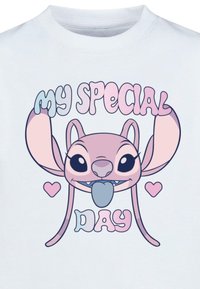 Svetlomodré tričko s karikatúrou postavy s veľkými ušami a ružovým dizajnom. Text hovorí "Môj špeciálny deň" v hravých písmach.