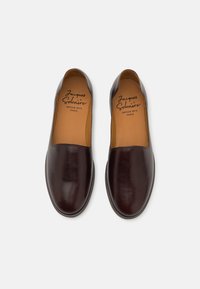 Brune lær slip-on sko med rund tå og glat tekstur. Indvendigt har de en tan indersål med branding. Minimalistisk design.