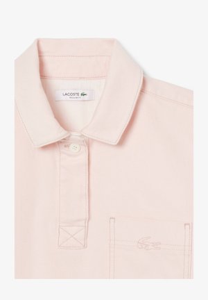 Polo shirt rosa chiaro con colletto classico, chiusura con un semplice bottone e taschino sul petto; presenta un logo ricamato e un tessuto testurizzato.