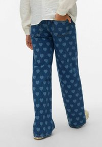 Mėlyni džinsai su platėjančiomis kojinėmis, puoši ant jų kartojantis šviesesnės spalvos širdelių raštas, tradicinių kišenių ir atlenktais kraštais.