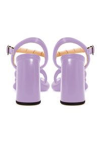 Tacchi alti viola con finitura lucida, tacco spesso a blocco, schiena aperta e cinturino alla caviglia regolabile. Presentano una soletta imbottita e un design elegante.
