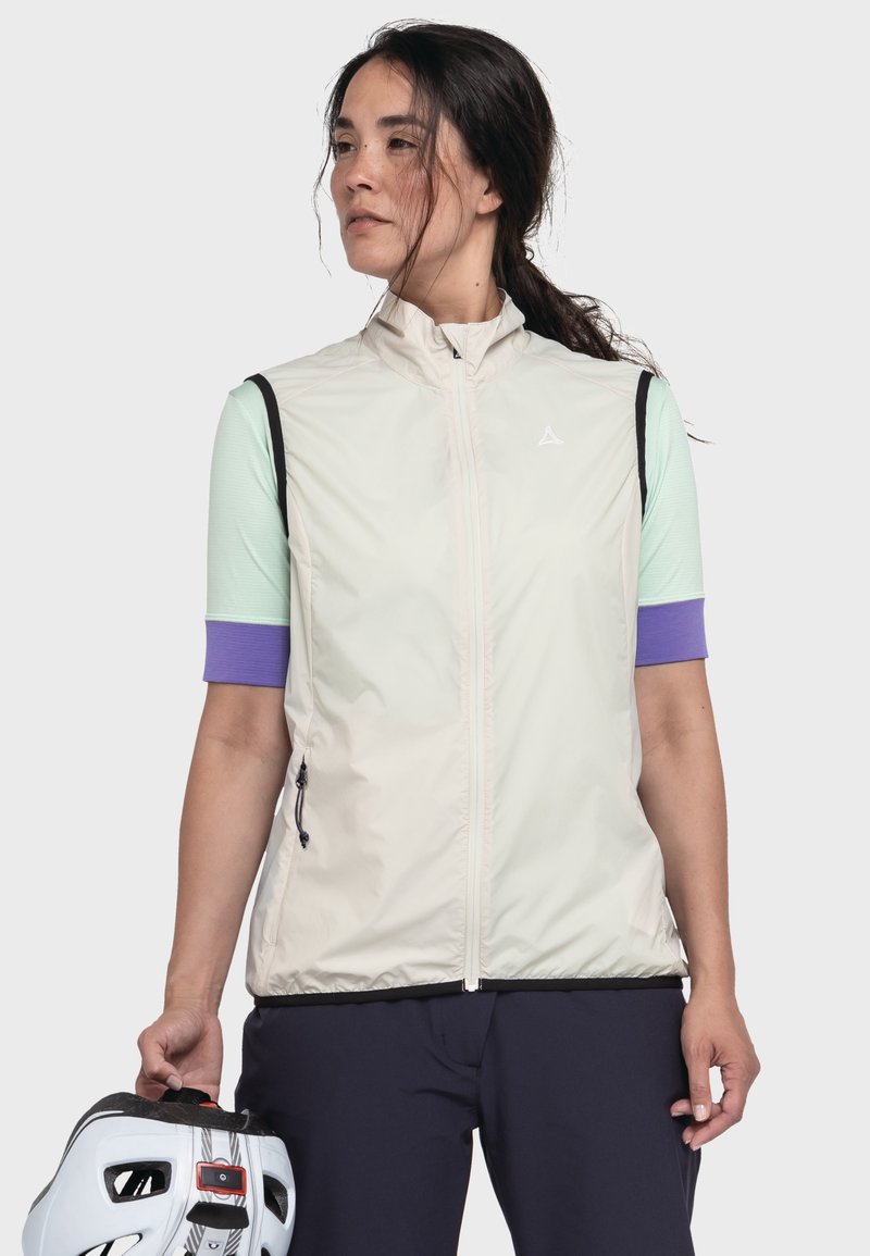 Leichte, cremefarbene Weste mit hohem Kragen, schwarzem Besatz und Reißverschlusstaschen, kombiniert mit einem mintfarbenen Shirt und lila Ärmeln, gehalten von einer Person.