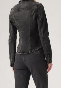 Mustat denimitakki, jossa on istuva muotoilu, klassinen kaulus, näkyvät ompeleet ja kapeneva vyötärö, yhdistettynä matching mustiin farkkuihin.