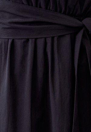 Must mustri kleit, millel on kogutud talje, lipsuga vöö ja voolavad pealised, millel on pehme tekstuur ja matt viimistlus.