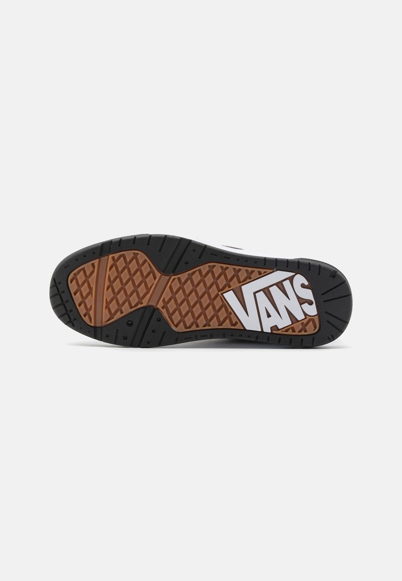 Semelle extérieure en caoutchouc noir avec un motif de grip marron. Logo "VANS" blanc bien visible sur le côté. Bout arrondi et design de semelle texturée.