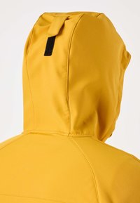 Keltainen huppari, jossa musta tarranauha hupun takana, kuvattuna takaa yläosasta.