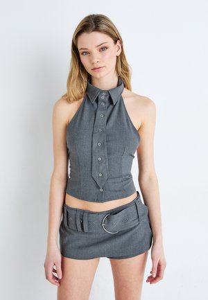 Top corto grigio con allacciatura a halter, colletto a punta e una mini gonna abbinata con una cintura larga e una fibbia circolare.