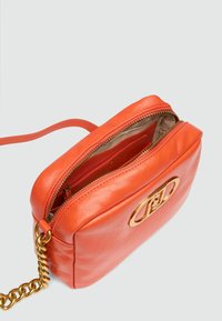 Geantă de umăr din piele portocalie, cu un strap din lanț aurit, închidere cu fermoar și formă rectangulară rotunjită. Prezintă hardware cu logo pe față.