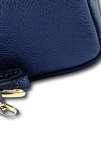 Marine leren portemonnee met een gladde textuur, voorzien van een gouden rits en hardware. Gebogen randen zorgen voor een compacte, slanke uitstraling.