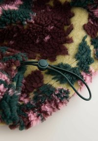 Pestrofarebná fleecová deka s kvetinovým vzorom v burgundskej, zelenej a ružovej farbe, so zeleným sťahovacím šnúrkou a textúrovaným povrchom.