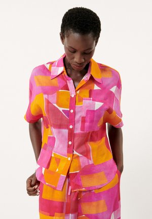 Chemise à manches courtes avec un motif géométrique en rose vif, orange et jaune, dotée d'une poche poitrine et d'une texture similaire au lin.