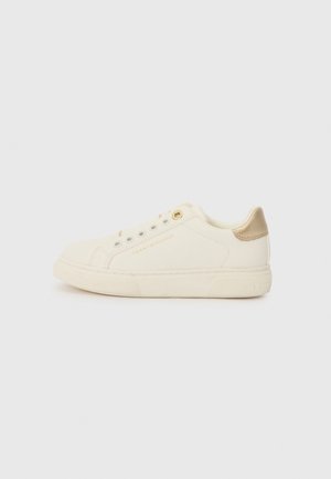 White canvas sneaker with beige accents, round toe, minimalistic design, gold eyelets, and brand logo printed on the side.