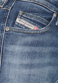 Blå denimjeans har en klassisk passform med en blekt behandling, kontrasterande gula sömmar och en liten logotag i framfickan.