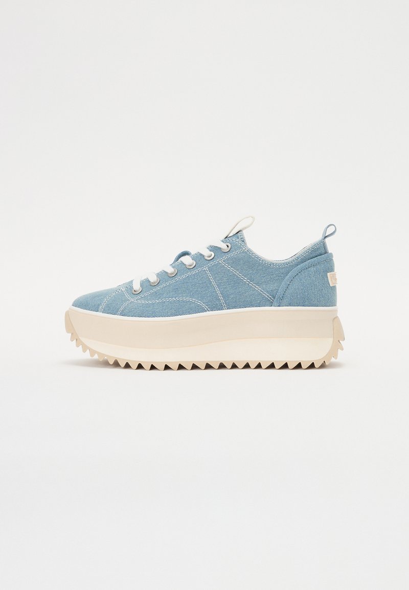 Sneaker in denim con parte superiore azzurra chiara, lacci bianchi e una robusta suola piattaforma color crema con battistrada a zigzag.