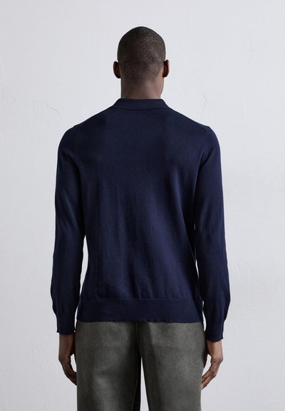 Marinblå långärmad tröja med krage och ribbade manschetter. Lätt stickad tyg med en tight silhuett och ren, minimalistisk design.