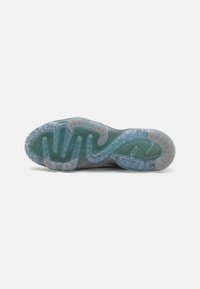 Shoe sole with a wavy, translucent design in gray and blue tones, featuring textured ridges and a pattern for traction.