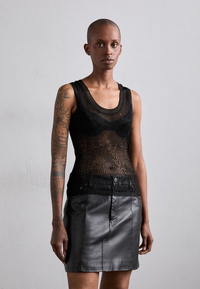 Schwarzes Stricktanktop mit einem strukturierten Muster, kombiniert mit einem schwarzen Minirock aus Leder, der eine glatte Oberfläche und einen vorderen Nahtdetails aufweist.