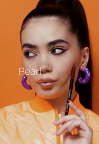 Veste bomber orange avec un col haut, boucles d'oreilles en forme de créole violettes, crayon à lèvres brun, peau lisse et maquillage neutre. L'arrière-plan est orange.